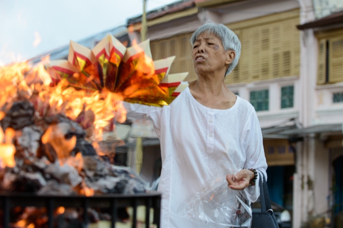 A member of the Yap clan burns paper money at Yap Kongsi clan house.