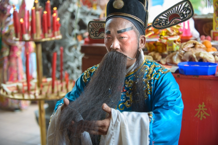 A Chinese Opera performer adopts an exaggerated pose to appease their clan god. Image: Altai World Photography.